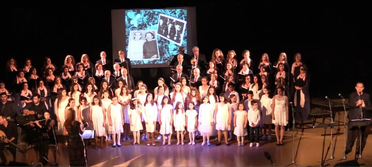 Adult and youth choir performing on stage with archival photographs projected behind them