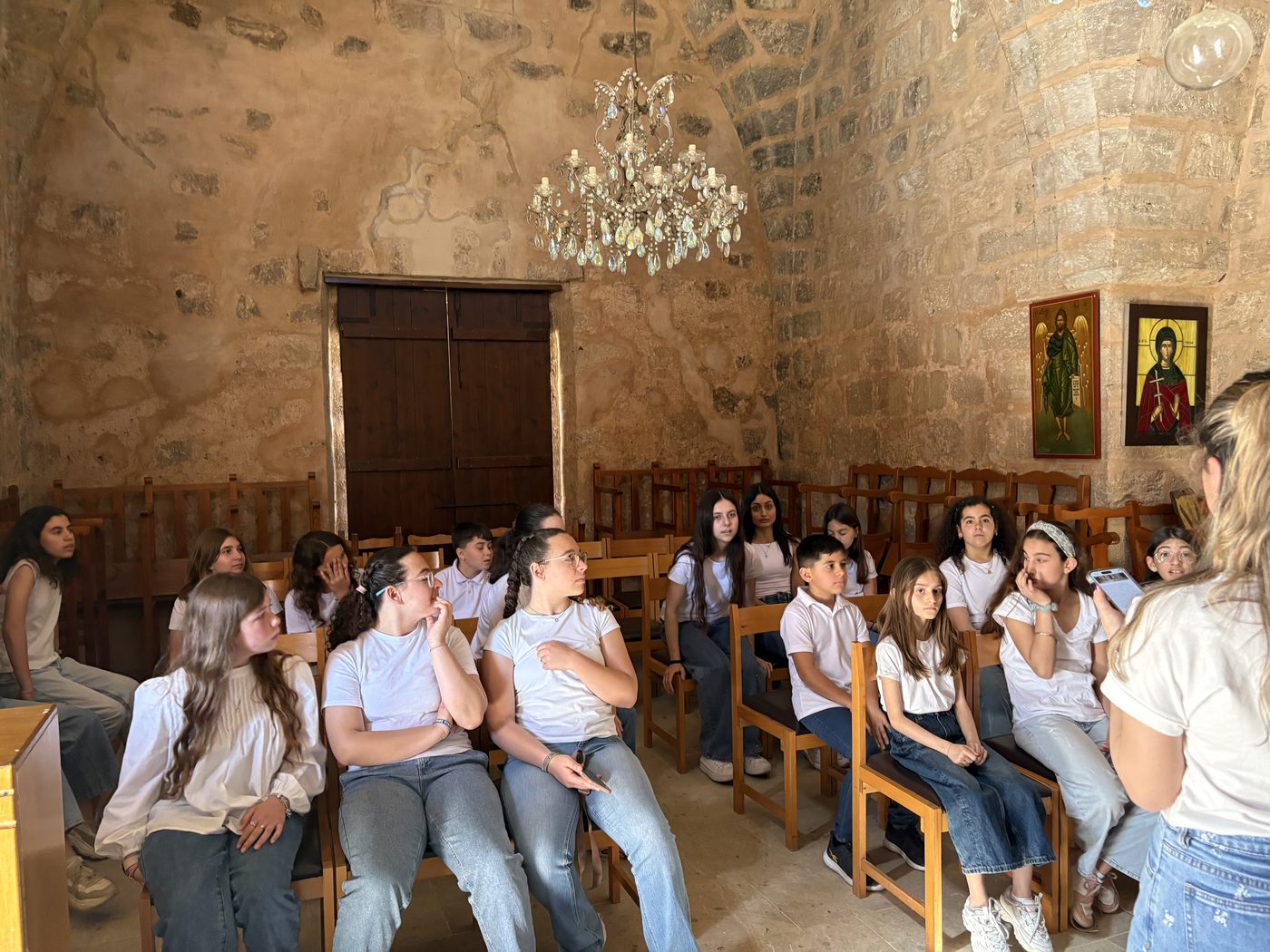 Young people seated inside a stone chapel during a cultural exchange visit