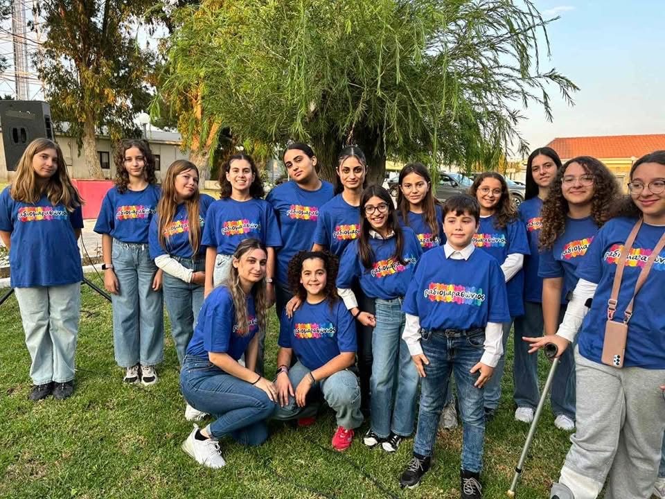 Group of young volunteers in matching blue t-shirts posing outdoors